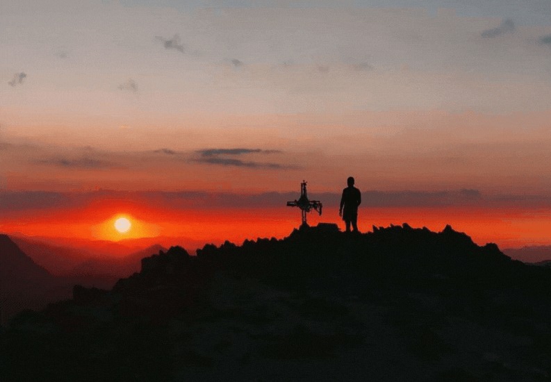 Hiker silhouette at sunset on a highland summit